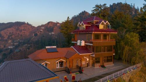 a large house on top of a mountain at Alaya Stays Lafu Woodscave Room with Attic & Hill views in Shimla
