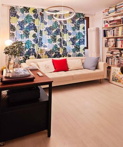 a living room with a couch with two red pillows at The best trip of my life at Suwon Haenggung, 4 people, Changnyongmun, relaxation, love stay, essence of Airbnb, beam TV, healing and love stay in Suwon
