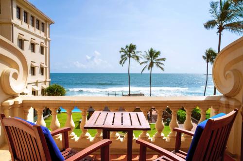 a table and chairs on a balcony overlooking the ocean at Galle Face Hotel in Colombo