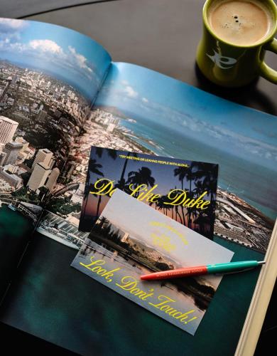 a book with two photos and a cup of coffee at Romer House Waikiki in Honolulu