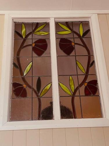 a window with a stained glass window with leaves on it at Charming 1-Bed Farm Cabin with Wood Fire in Tenterfield