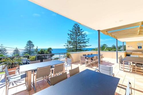 a patio with tables and chairs and the ocean at Beachfront Apartments in Port Macquarie