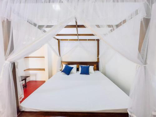 a bedroom with a white bed with blue pillows at Villa Vinuth Bliss in Mirissa