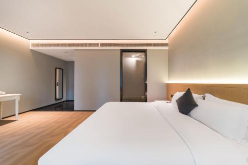 a bedroom with a large white bed and a desk at Quanzhou Fengze Square West Street Wanxin Zhige Hotel in Quanzhou