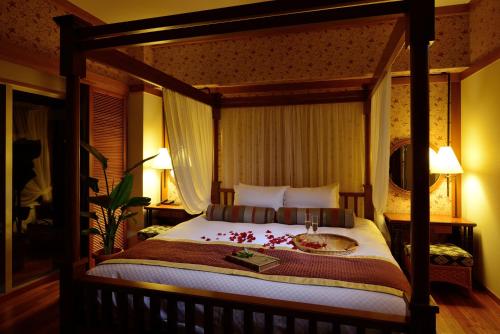 a bedroom with a large bed with a wooden canopy at Kanucha Bay Hotel & Villas in Nago