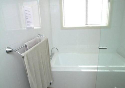 a white bathroom with a shower and a towel at Elanora Tranquility at Emu Bay in Emu Bay