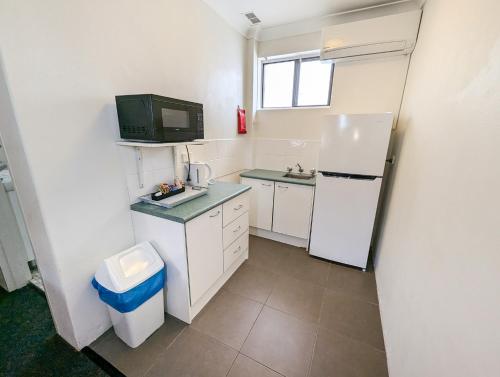 a small kitchen with a refrigerator and a sink at Bella Villa Motor Inn in Forster