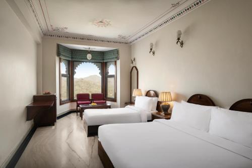 a hotel room with two beds and a window at Bhairavgarh Palace Udaipur in Udaipur
