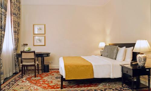 a hotel room with a bed and a desk and a table at Galle Face Hotel in Colombo