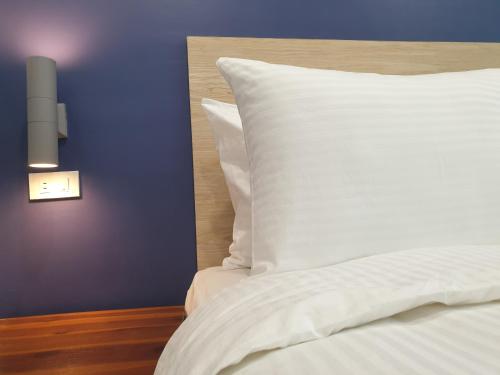 a bed with a white pillow next to a purple wall at Leez Inn Makati in Manila