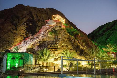 a building on the side of a mountain at night at Dibba Mountain Park Resort in Fujairah