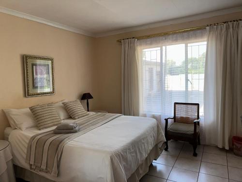 a bedroom with a bed and a window and a chair at Guesthouse 52 in Groblersdal