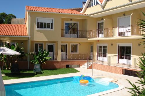 a villa with a swimming pool in front of a house at Hotel Rural Solar Das Freiras in Figueiró dos Vinhos