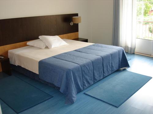 a bedroom with a bed with blue rugs on the floor at Hotel Rural Solar Das Freiras in Figueiró dos Vinhos