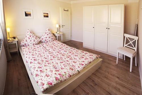 Un dormitorio con una cama grande y una silla. en 27 Ferienwohnung an der Reiterkoppel 49a EG, en Burg auf Fehmarn