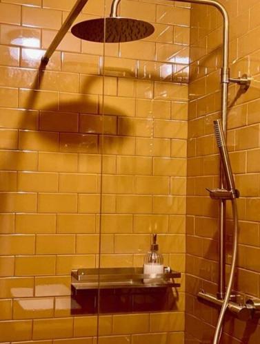 La salle de bains est pourvue d'une douche et d'un mur carrelé jaune. dans l'établissement Face à la plage STUDIO avec grande terrasse au calme, à Marseille