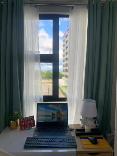 a laptop computer sitting on a desk in front of a window at Modern Condo, Sea View, Fast Wifi, Cafe, Panglao in Dauis