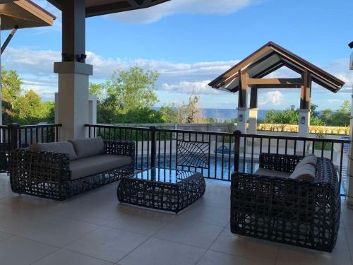 a patio with a couch and chairs on a balcony at Modern Condo, Sea View, Fast Wifi, Cafe, Panglao in Dauis