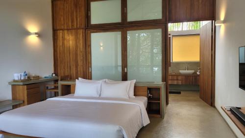 a bedroom with a bed and a bathroom with a sink at Arachchi Heritage in Anuradhapura