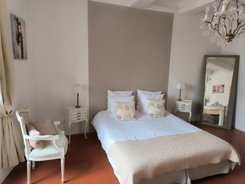 a bedroom with a bed and a chair and a mirror at Les Chambres De Charlotte in Cucuron