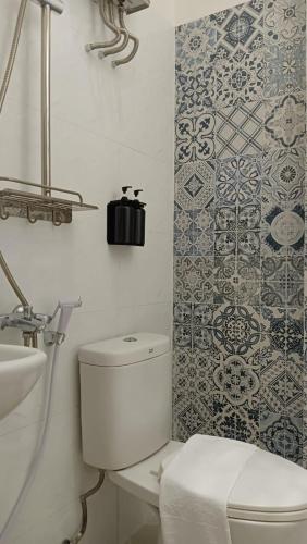 a white bathroom with a toilet and a tile wall at Casaluna Bed & Breakfast By Avalon in Purwokerto