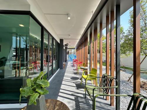 a building with green chairs and tables and windows at BB HOUSE Rangsit in Ban Talat Rangsit