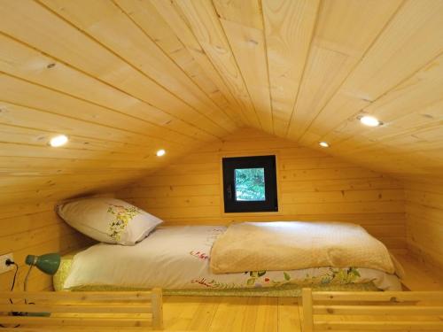 a bed in a log cabin with a ceiling at Tiny somniflore in Wasigny