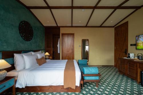 a bedroom with a large white bed and blue chairs at The Mist Boutique DaLat Hotel in Da Lat