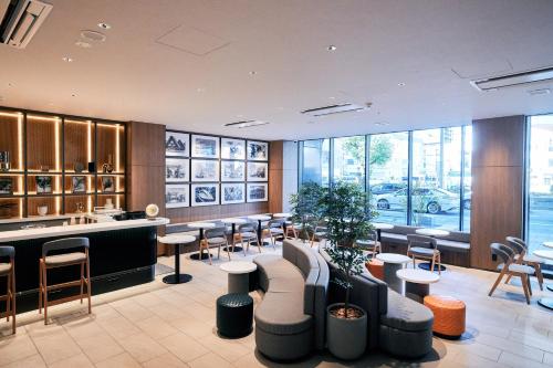a restaurant with a bar with stools and tables at Compass Hotel Nagoya in Nagoya