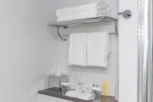 a bathroom with white towels and a shelf with towels at DoubleTree by Hilton Hotel London - Tower of London in London