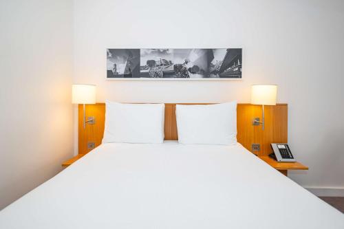 a bedroom with a large white bed with two lamps at DoubleTree by Hilton Hotel London - Tower of London in London