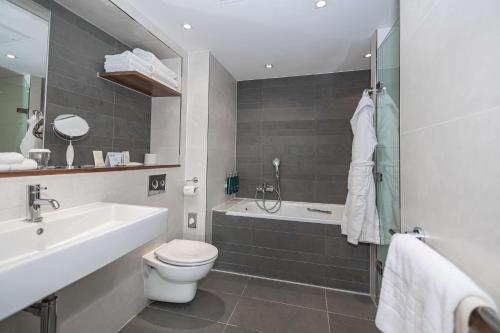 a bathroom with a sink and a toilet and a bath tub at DoubleTree by Hilton Hotel London - Tower of London in London