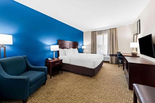 a hotel room with a bed and a blue wall at Comfort Inn & Suites Near Lake Lewisville in Corinth