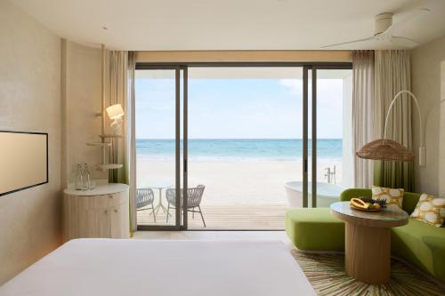 a bedroom with a room with a view of the beach at Centara Mirage Lagoon Maldives in Nakachchafushi