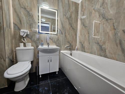 Un baño con inodoro, bañera y lavabo. en Aparthotel Militari, en Roşu