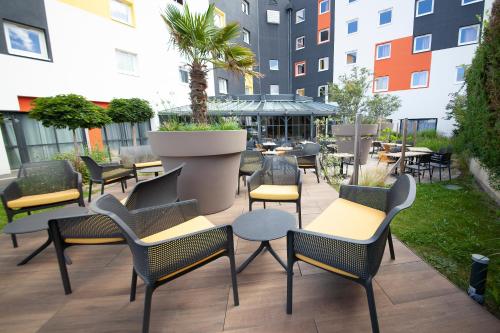 une terrasse avec des chaises, des tables et une plante en pot dans l'établissement The Originals Boutique, Hôtel Le Marmotel, Clermont-Ferrand, à Clermont-Ferrand