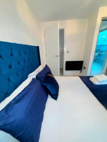 a large bed with blue pillows in a bedroom at Winners of 2025 traveller Award, Elegant two bedroom city central apartment with Netflix & WiFi in Leeds