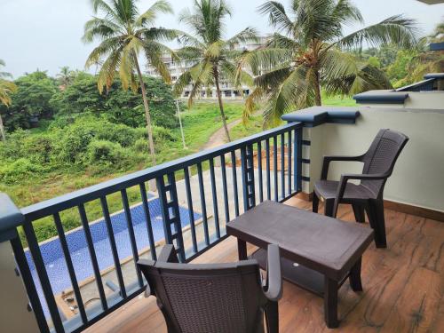 a balcony with chairs and a table and a pool at Beach Bliss Apartment Hotel - 7 Minutes walk to Beach in Colva