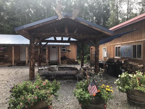 a wooden cabin with an american flag in a yard at talkeetna villas and tours in Talkeetna