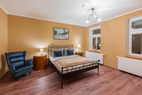 a bedroom with a bed and a blue chair at Apartmány za Královskou mincovnou in Jáchymov