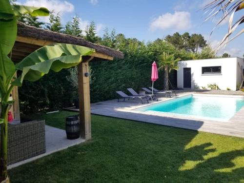 une cour arrière avec une piscine et une maison dans l'établissement Villa familiale 10min de l'océan piscine chauffée, à Saubion