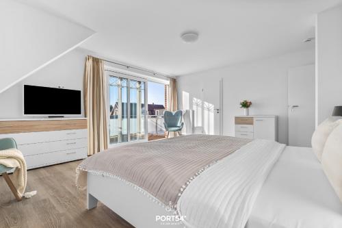 a white bedroom with a large bed and a television at Ferienhaus Buhne 23 in Büsum