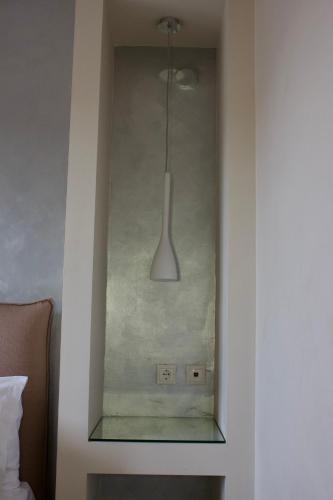 a glass cabinet in a bedroom with a light fixture at Notos Luxury Studios in Katelios