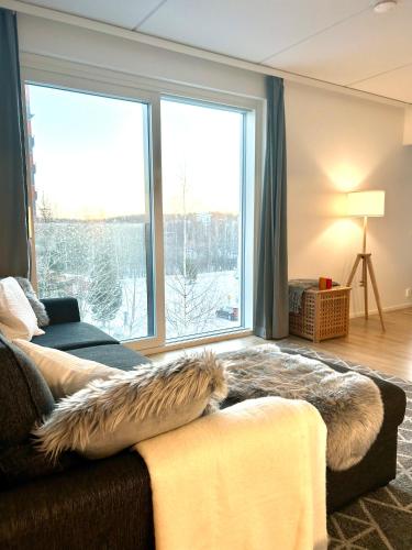 a living room with a couch and a large window at Moderni viihtyisä kaksio Jyväskylässä ilmaisella pysäköintipaikalla in Jyväskylä