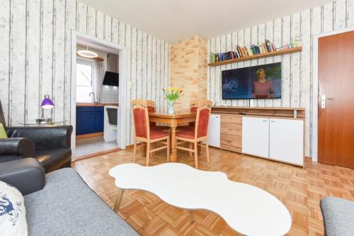 a living room with a table and a kitchen at Haus Kajedeich FeWo Seestern in Bensersiel