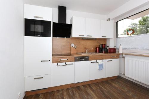 a white kitchen with white cabinets and a window at Haus zur Möwe FeWo Möwe 5 in Bensersiel