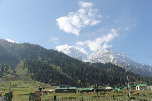 a green field with mountains in the background at Hotel Barzman in Sonāmarg