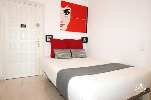 a bedroom with a white bed with red pillows at Holidays 15K Empuriabrava in Empuriabrava