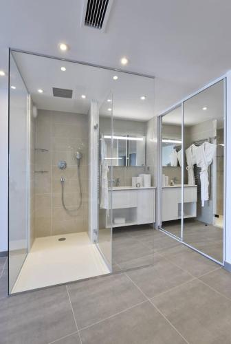 La salle de bains est pourvue d'une douche avec des parois en verre. dans l'établissement NAUTILIA 106 - Supérieure Luxe avec Jacuzzi 2 personnes, au Cap d'Agde