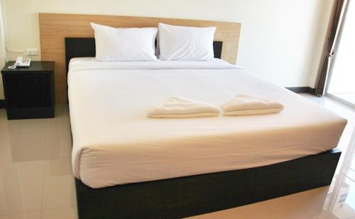 a large bed with two white towels on it at Baansiri Chiangrai in Chiang Rai